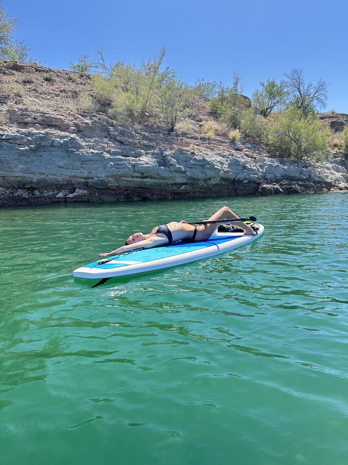Hannah relaxing on a paddleboard on a turquoise lake